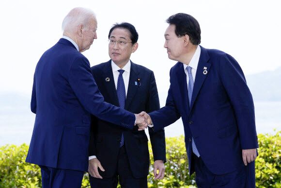 윤석열 대통령(오른쪽)과 조 바이든 미국 대통령(왼쪽)이 21일 일본 히로시마에서 주요 7개국(G7) 정상회의를 계기로 열린 한·미·일 정상회담을 앞두고 기시다 후미오 일본 총리가 지켜보는 가운데 악수하고 있다.