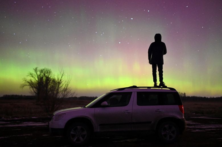 지난 6일 러시아 시베리아 옴스크 지역에서 오로라를 바라보며 한 사람이 차 위에 서 있다. 로이터 연합뉴스