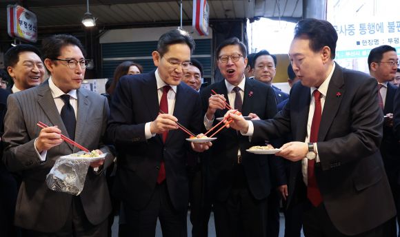 윤석열 대통령이 6일 부산 중구 깡통시장에서 재계 총수들과 분식을 맛보며 이재용 삼성전자 회장, 조현준 효성그룹 회장에게 빈대떡을 나눠주고 있다.  2023.12.6 연합뉴스