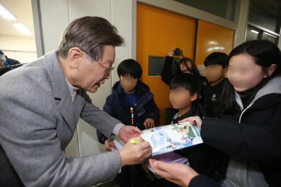 이재명 더불어민주당 대표가 6일 오후 서울 강서구 방화초등학교에서 ‘온동네 초등돌봄’ 정책 현장간담회에 앞서 돌봄 교실을 둘러보다가 초등학생들에게 사인을 해주고 있다. 2023.12.06