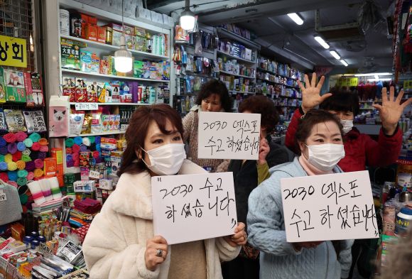 윤석열 대통령의 방문을 앞두고 6일 부산 중구 깡통시장에서 부산 시민들이 윤 대통령의 부산엑스포 유치활동에 대한 감사 메시지를 보여주며 환영하고 있다.  2023.12.6 연합뉴스