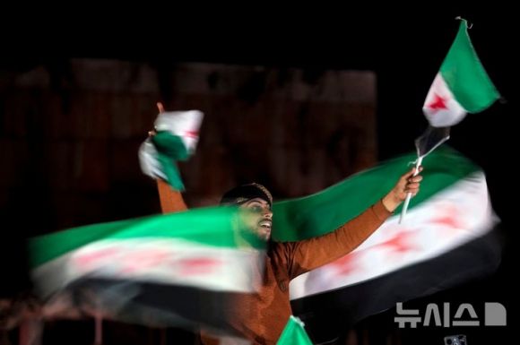 지난 13일(현지시각) 시리아 알레포에서 바샤르 알아사드 정권 축출 이후 첫 금요 예배를 마친 시리아인들이 ‘혁명’ 깃발을 들고 정권 붕괴를 축하하고 있다. AP 뉴시스