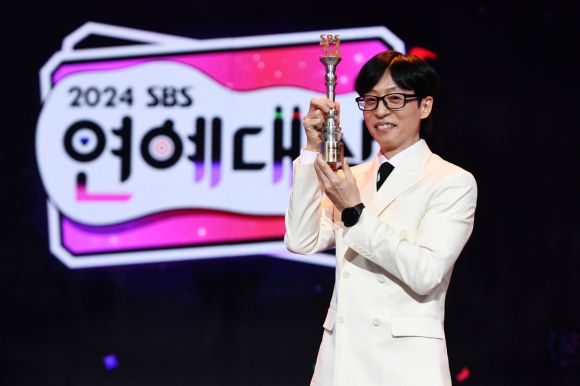 유재석이 지난 29일 서울 마포구 SBS프리즘타워에서 열린 ‘2024 SBS 연예대상’에서 개인 통산 20번째 대상을 받은 뒤 트로피를 든 채 활짝 웃고 있다.  SBS 제공
