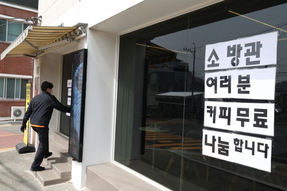 ‘진화대원에게 커피 무료로 나눕니다’ - 25일 경북 의성 산불이 나흘째 잡히지 않는 가운데 한 의성읍 의성종합운동장 인근 카페 유리창에 소방관 등 진화대원들에게 커피를 무료로 나눈다는 안내문이 붙어있다. 사진은 이날 해당 카페 인근에서 소방용수시설을 점검한 한 소방관이 커피를 받기 위해 방문하는 모습. 2025.3.25 연합뉴스