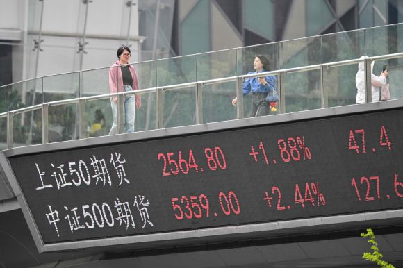 9일 상하이의 금융 지구에서 세계 주요 증시 가운데 중국만 유일하게 상승한 지수가 표기된 인도교를 행인들이 걷고 있다. 상하이 AFP 연합뉴스