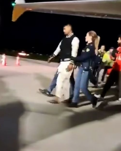 지난 21일 이탈리아의 한 공항에 서 있던 비행기의 랜딩 기어 박스에서 발견된 남성이 경찰과 함께 이동하고 있다. 영상 캡처