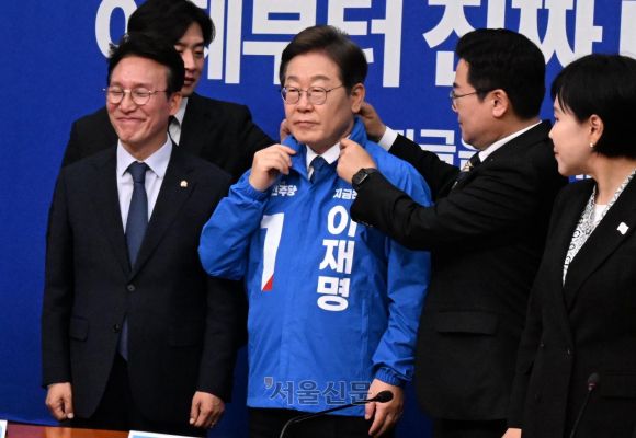 이재명 더불어민주당 대선 후보가 28일 국회에서 열린 당 최고위원회의에서 빨간색 점이 찍힌 선거운동용 파란색 점퍼를 입고 있다. 박찬대 당대표 직무대행 겸 원내대표가 이 후보의 옷매무새를 만져주고 있다. 2025.4.28 안주영 전문기자