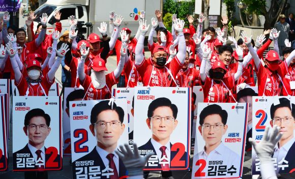 국민의힘 충북도당 선거대책위원회가 지난 13일 충북 청주시 성안길에서 열린 출정식에서 국민의힘의 기호인 ‘2’가 적힌 장갑을 양손에 낀 채 두 팔을 번쩍 치켜들고 있는 모습. 청주 뉴시스