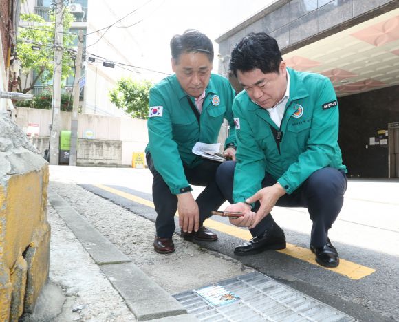 박준희(오른쪽) 서울 관악구청장이 지난 20일 청룡동의 한 골목길에서 스마트 빗물받이 QR코드를 점검하고 있다. 관악구 제공