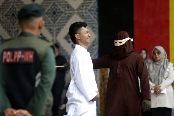 4일(현지시간) 인도네시아 수마트라섬 서부 아체주 반다아체에 있는 공원에서 한 남성이 공개 태형을 받고 있다. 이 남성은 여성과 혼외 성관계를 한 혐의로 유죄를 선고받았다. EPA 연합뉴스