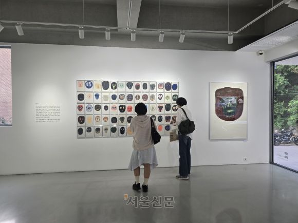 크라우더의 ‘얼굴들’ 연작을 감상하는 관람객의 모습. 이 작품은 그림책의 경계를 넘어 현대 미술로 확장한 크라우더의 예술적 도전을 보여 준다.