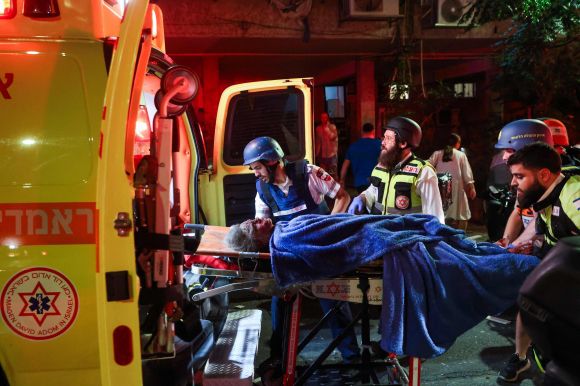 이스라엘 응급 구조대원들이 2025년 6월 13일(현지시간) 텔아비브 외곽 라맛간에서 이란에서 발사된 미사일에 맞은 현장에서 부상당한 주민을 이송하고 있다. AFP 연합뉴스