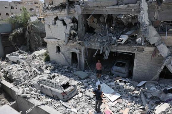 이스라엘 북부 마을 탐라의 주민들이 15일 전날 이란의 미사일 폭격으로 피해를 입은 건물을 살펴보고 있다. AFP 연합뉴스