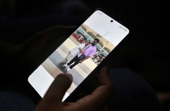 스마트폰 속 오른쪽 남성은 지난 12일 인도에서 발생한 최악의 비행기 추락사고의 희생자 중 한명인 로렌스 다니엘 크리스찬(30). 왼쪽은 그의 어머니. 로이터 연합뉴스