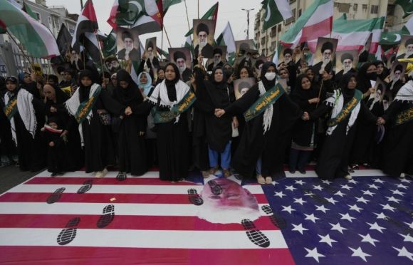 22일(현지시간) 파키스탄 카라치에서 이란에 대한 이스라엘의 공습을 비난하는 집회에 참석한 시아파 무슬림들이 미국 국기 위에 서 있다.  AP 연합뉴스