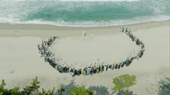 배우 유준상이 연출한 영화 ‘청명과 곡우 사이’의 한 장면. 박정자(가운데)가 그가 출연한 작품의 제목이 적힌 만장을 든 150명의 지인들에게 둘러싸여 있다. 쥬네스엔터테인먼트 제공