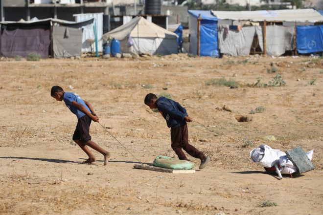 팔레스타인 소년들이 2025년 7월 7일(현지시간) 가자지구 중부 알부레이 수용소 근처 쓰레기장에서 구한 고물을 끌고 가고 있다. AFP 연합뉴스