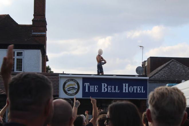 14일(현지시간) 영국 에식스주 에핑 중심가에 있는 3성급 호텔 ‘더 벨’ 앞에서 반이민 단체가 시위를 벌이고 있다. 이 호텔  위에는 한 남성이 올라가 있다. 출처=이브닝 스탠더드