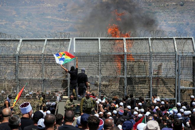 2025년 7월 16일(현지시간) 시리아 드루즈 지역에서 충돌이 이어지는 가운데 이스라엘-시리아 국경인 마즈달 샴스에서 드루즈 주민들이 양측에 서 있다. 로이터 연합뉴스