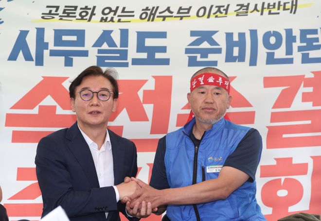 전재수 해양수산부 장관 후보자가 17일 서울 여의도 국회 앞에서 해수부 부산 이전 반대 단식 투쟁 중인 윤병철 공무원노조 해수부지부 위원장과 만나 대화하며 손을 잡고 있다. 윤 위원장은 이날 전 후보자와의 만남에서 단식 투쟁 중단을 선언했다. 연합뉴스