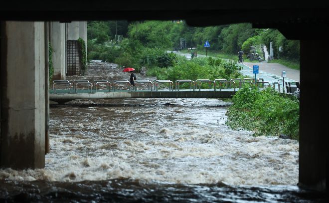 ‘위험해요’ - 서울 전역에 호우주의보가 발효 중인 가운데 17일 물이 불어나고 있는 서울 서대문구 홍제천 산책로 위를 우산을 쓴 시민이 지나고 있다. 2025.7.17 연합뉴스