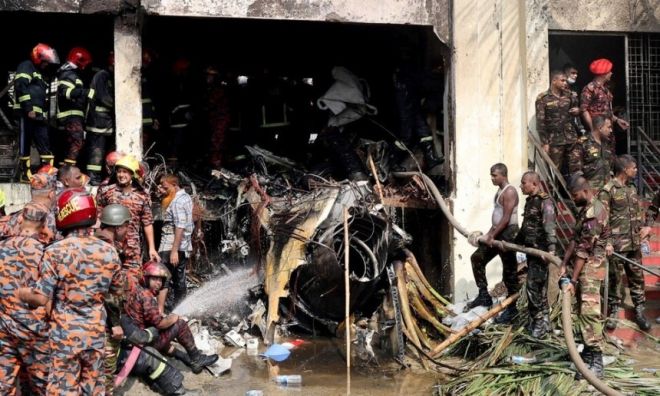 21일 방글라데시 다카에서 공군 훈련기가 한 학교 캠퍼스에 추락한 뒤 소방대원들과 군인들이 추락 기체 잔해 옆에 서 있다. 로이터 연합뉴스