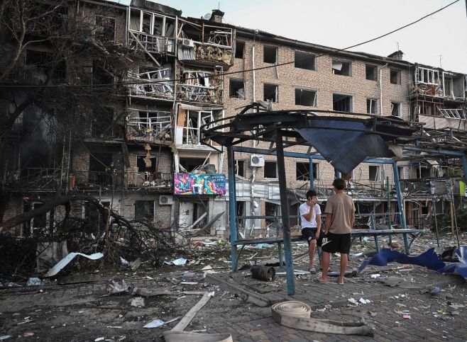 30일(현지시간) 우크라이나 자포리자에서 러시아의 드론·미사일 공습으로 피해를 본 아파트 건물 앞에 주민들이 서 있다. 로이터 연합뉴스