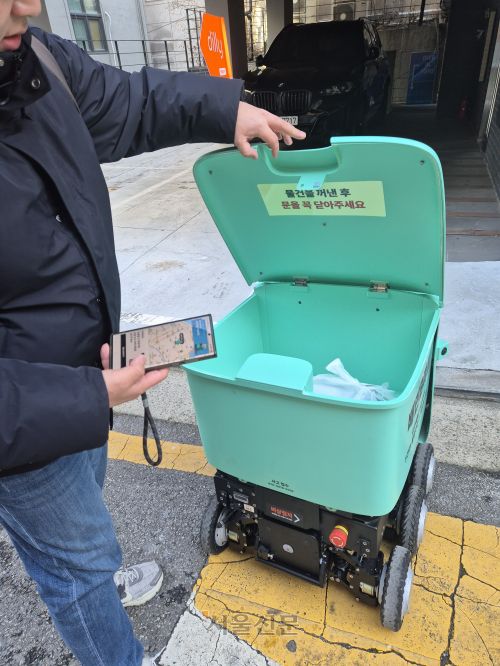 배민B마트 앱을 이용한 소비자가 지난 13일 서울 논현동의 한 건물 앞에서 딜리를 열어 주문한 물품을 확인하고 있다.