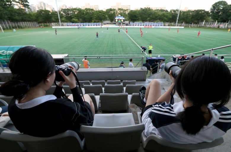 WK리그 경기 직관이 네 번째라는 최예슬(23·왼쪽)씨가 2025년 7월21일 저녁 서울 마포구 상암동 서울월드컵경기장 보조경기장에서 열린 서울시청 아마조네스(검은색 유니폼)와 인천현대제철 레드엔젤스WFC의 경기를 사진에 담고 있다. 이종근 선임기자 root2@hani.co.kr