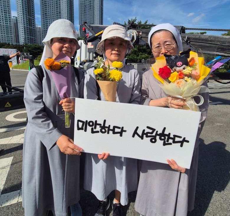 박정혜 수석부지회장이 600일로 고공농성을 해제한 2025년 8월29일 천주교 수녀들이 박 부지회장에게 줄 꽃다발과 손팻말을 들어보이고 있다. 신다은 기자