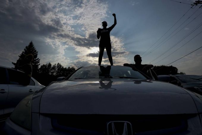 [커노샤=AP/뉴시스] 지난 24일(현지시간) 미 위스콘신주 커노샤에서 시위대가 도로를 막고 시위를 벌이는 가운데 한 남성이 자동차 위에 올라가 구호를 외치고 있다. 2020.08.25.