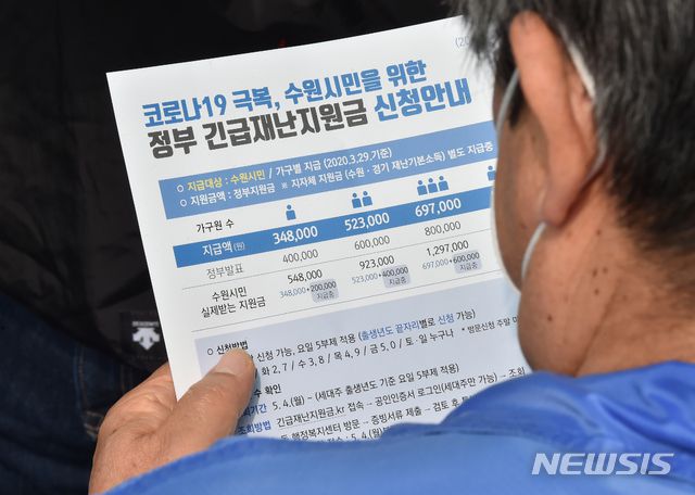 [수원= 뉴시스] 김종택기자 = 정부가 추진하는 코로나19 긴급재난지원금 현장신청 첫날인 18일 오전 경기 수원시 권선구 세류2동 행정복지센터에서 한 신청자가 안내문을 살펴보고 있다. 2020.05.18.  semail3778@naver.com