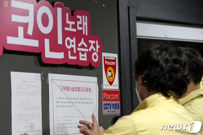 (서울=뉴스1) 이승배 기자 = 신종 코로나바이러스 감염증(코로나19) 확산 예방을 위해 사회적 거리두기 2단계가 시행된 19일 오후 서울 송파구 일대에서 구청 관계자가 한 코인노래연습장에 코로나19 확산 억제를 위한 집합금지명령문을 붙이고 있다. 2020.8.19/뉴스1