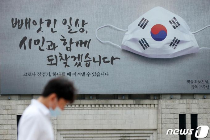 2일 서울광장에서 시민들이 출근길을 서두르고 있다. 서울도서관 외벽에 '빼앗긴 일상, 시민과 함께 되찾겠습니다', '코로나 강점기, 하나될 때 이겨낼 수 있습니다'라는 문구와 태극기가 새겨진 마스크 그림의 꿈새김판이 눈에띈다. /사진=뉴스1