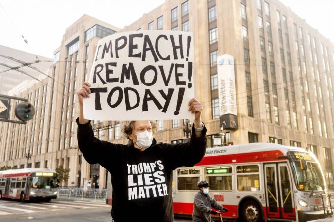 11일(현지시간) 미 캘리포니아주 샌프란시스코 트위터 본사 앞에서 한 시민이 도널드 트럼프 대통령의 탄핵을 촉구하는 손팻말을 들고 1인 시위를 벌이고 있다. 이날 경찰은 보수단체 시위에 대비해 울타리를 치고 시위에 대비했다./사진=[샌프란시스코=AP/뉴시스]