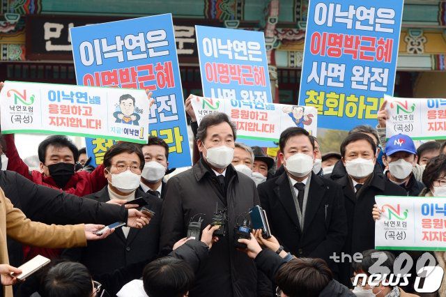 (광주=뉴스1) 정다움 기자 = 이낙연 더불어민주당 대표가 18일 오후 광주 북구 운정동 국립5·18민주묘지에서 참배를 마친 뒤 민주의문 앞에서 기자들의 질문에 답하고 있다. 이 대표 뒤로 시민들이 '이낙연은 이명박근혜 사면 완전 철회하라'는 피켓을 들고 서 있다. 2021.1.18/뉴스1