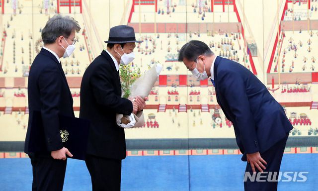 [서울=뉴시스]추상철 기자 = 문재인 대통령이 15일 오전 청와대 본관에서 권칠승 중소벤처기업부 장관 부친에게 꽃다발을 전달한 후 인사하고  있다. 2021.02.15. scchoo@newsis.com