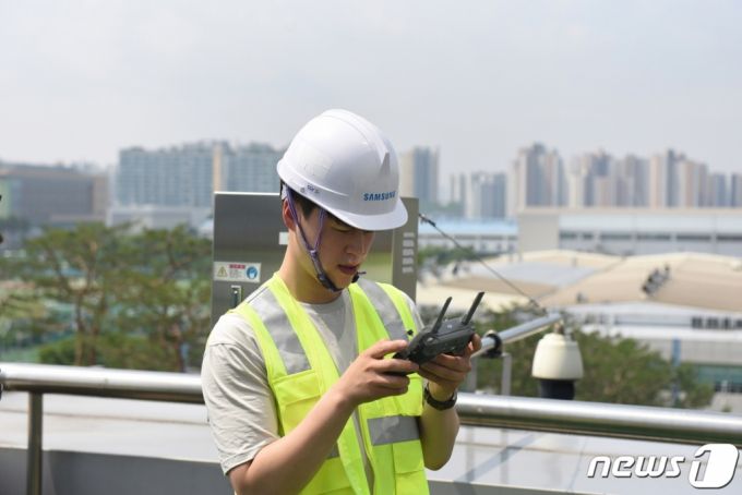 (서울=뉴스1) = 삼성전자가 드론과 인공지능(AI)을 활용해 기지국과 안테나의 설치 상태를 분석해 5G 네트워크의 성능을 신속하고 정확하게 최적화하는 솔루션을 23일 공개했다. 이번 솔루션은 기지국과 안테나의 설치 각도를 드론을 활용해 측정하기 때문에 빌딩 등 높은 고도에 설치되어 있는 장비도 작업자의 안전 문제 없이 손 쉽게 확인이 가능하며, 장비와 근접 촬영이 가능해 측정 오차 수준도 최소화 할 수 있다. 삼성 5G 네트워크 성능 최적화 솔루션 개발자가 기지국과 안테나 각도 측정을 위해 원격에서 드론을 조종하고 있는 모습. (삼성전자 제공) 2020.6.23/뉴스1