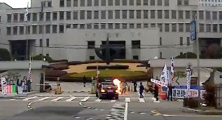 = 27일 오전 김명수 대법원장 출근길 차량이 대법원 정문 앞을 지날 때 한 남성이 화염병을 투척하고 있다. (김정수씨 제공)2018.11.27/뉴스1