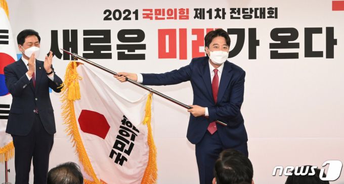 이준석 국민의힘 신임 대표가 11일 오전 서울 영등포구 국민의힘 당사에서 열린 전당대회에서 당기를 흔들고 있다. '30대·0선'의 이 대표는 역대급 전당대회 흥행을 주도한 끝에 헌정사상 최초의 30대 보수정당 대표에 올랐다. /사진=뉴스1