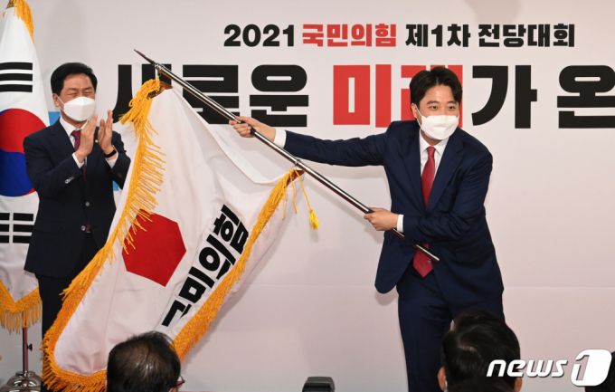 이준석 국민의힘 신임 대표가 11일 오전 서울 영등포구 국민의힘 당사에서 열린 전당대회에서 당기를 흔들고 있다. '30대·0선'의 이 대표는 역대급 전당대회 흥행을 주도한 끝에 헌정사상 최초의 30대 보수정당 대표에 올랐다. /사진=뉴스1