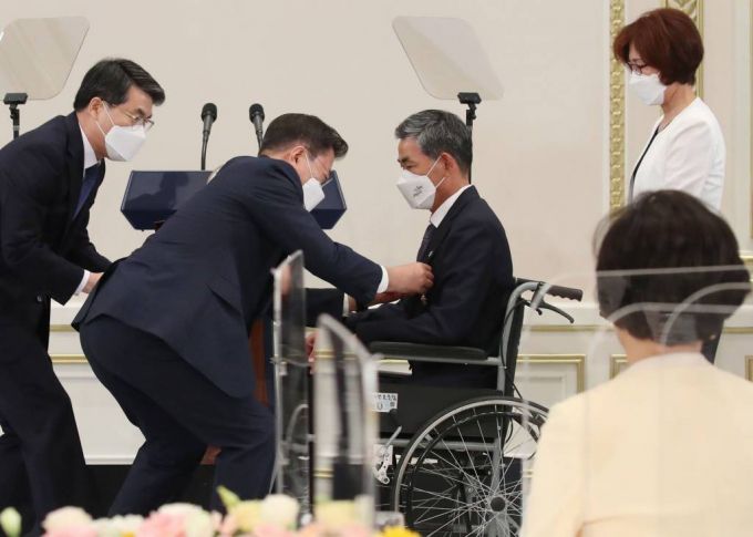 [서울=뉴시스김진아 기자 = 문재인 대통령이 24일 청와대 영빈관에서 열린 '국가유공자 및 보훈가족 초청 오찬'에 참석해 공상군경1급 중상이자인 서용규 씨에게 국민훈장 목련장을 수여하고 있다. 2021.06.24. bluesoda@newsis.com