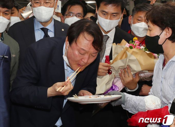 (부산=뉴스1) 부산사진공동취재단 = 윤석열 전 검찰총장이 27일 오후 부산 중구 자갈치시장을 찾아 상인이 건넨 전복을맛보고 있다. 2021.7.27/뉴스1