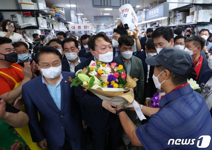 (부산=뉴스1) 부산사진공동취재단 = 윤석열 전 검찰총장이 27일 오후 부산 중구 자갈치시장에서 상인이 건넨 꽃다발을 받고 있다. 2021.7.27/뉴스1