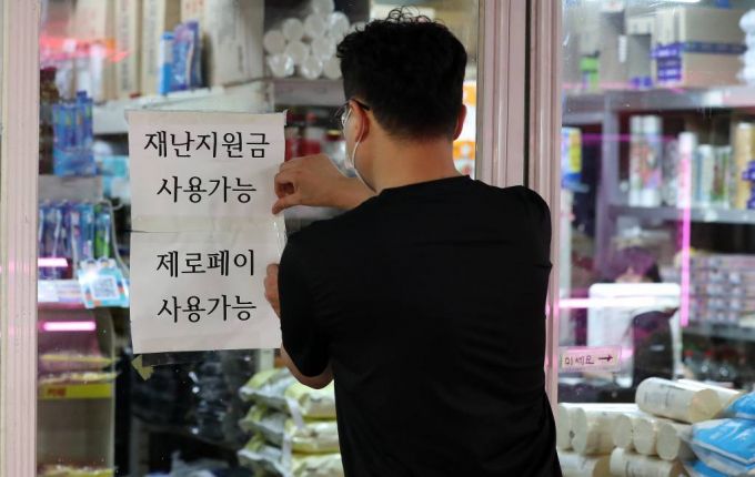 [서울=뉴시스] 백동현 기자 = 정부가 코로나 상생 국민지원금 세부시행계획을 발표한 30일 오후 서울 마포구 공덕역 인근 점포 주인이 재난지원금 사용 가능 안내문을 붙이고 있다. 상생 국민지원금은 9월 6일부터 10월 29일까지 전 국민의 약 88%에게 1인당 25만원씩 지급된다. 2021.08.30.