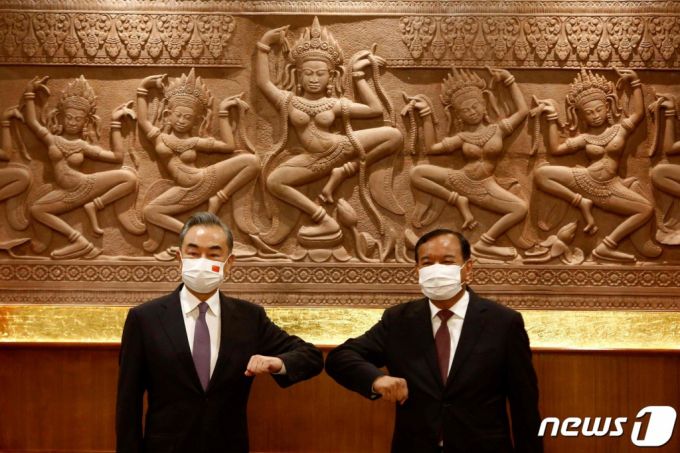 왕이 중국 외무장관이 12일(현지시간) 캄보디아 프놈펜 외교부에서 쁘락 소콘 부총리 겸 외교장관과 회담에 앞서 팔꿈치 인사를 하고 있다.  /AFP=뉴스1