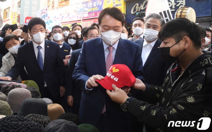 (서울=뉴스1) 국회사진취재단 = 윤석열 국민의힘 대선 경선 후보가 3일 오전 서울 중구 남대문시장에서 모자를 고르고 있다. 2021.11.3/뉴스1