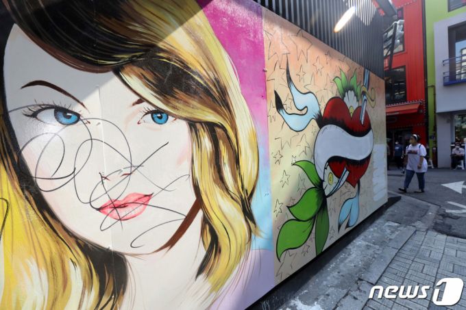 (서울=뉴스1) 황기선 기자 =  30일 오전 서울 종로구의 한 서점 벽면에 그려진 윤석열 전 검찰총장의 배우자 김건희 씨를 비방하는 내용의 벽화 문구가 페인트로 지워져 있다. 2021.7.30/뉴스1