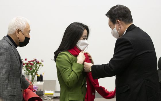(서울=뉴스1) 오대일 기자 = 윤석열 국민의힘 대선 후보가 20일 서울 여의도 새시대준비위원회 위원장실에서 열린 영입인사 환영식에서 신지예 한국여성정치 네트워크 대표에게 환영 목도리를 걸어주고 있다. 2021.12.20/뉴스1