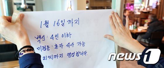 31일 서울 종로구 한 식당에서 종업원이 거리두기 연장관련 문구를 붙이고 있다. / 사진 = 뉴스1